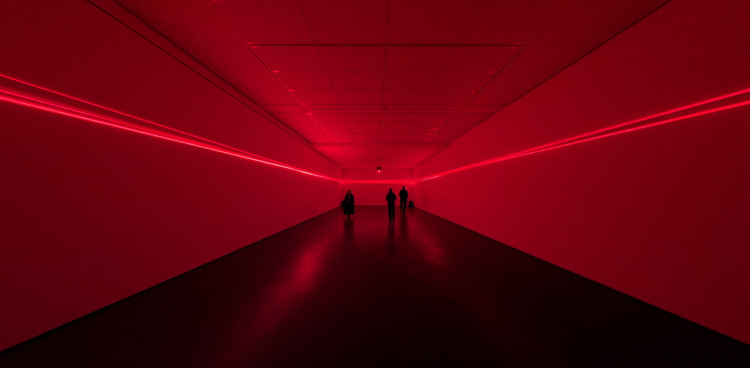 Scattered Horizon; red laser lights in exhibition space with three people